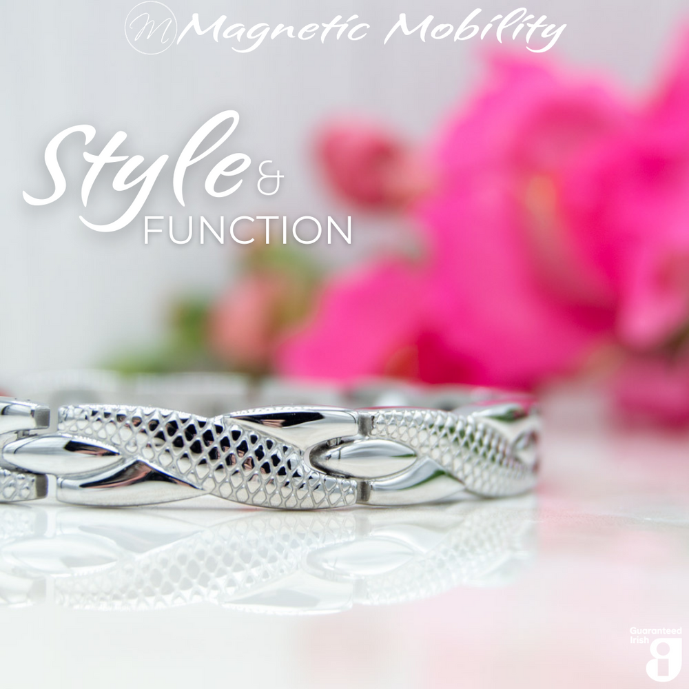 
                  
                    Load image into Gallery viewer, 45 degree view of the Snapdragon Star 4in1 magnetic bracelet by Magnetic Mobility. Shown on a reflective surface with pink flowers in the background. The text says &amp;quot;Style and Function&amp;quot; and &amp;quot;Designed for people with arthritis, back pain, fibromyalgia, joint and muscle pain, menopause symptoms, migraine and more&amp;quot;. 
                  
                