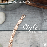 Top view of the Meadowsweet Dawn 4in1 Magnetic bracelet from Magentic Mobility featuring a butterfly design on rose gold stainless steel. The bracelet is shown on a wooden surface. 