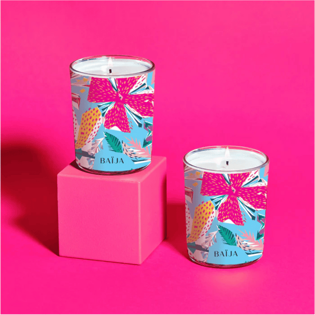 Two candles with colorful packaging on a pink background