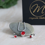 January Magnetic Mobility Birthstone Gift Set featuring a Magnetic Necklace and Stud Earrings featuring January garnet red Swarovski crystals, elegantly presented on a flat stone with a black box with Magnetic Mobility branding in the background. These magnetic back earrings offer stylish pain relief.