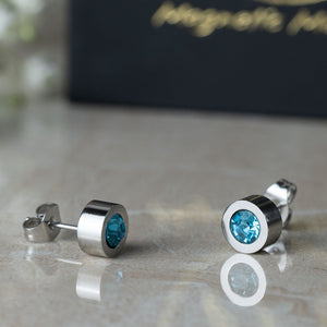 
                  
                    Load image into Gallery viewer, Magnetic Mobility Birthstone Stud Earrings featuring light blue Aquamarine Swarovski crystals. These earrings have a magnetic back and are designed for stylish pain relief, displayed on a reflective surface with Magnetic Mobility packaging.
                  
                