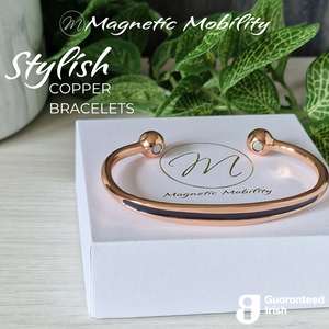 
                  
                    Load image into Gallery viewer, 45 degree view of the Spindle Dawn Copper bracelet from Magnetic Mobility. A copper bracelet with a simple design and an white band in the centre. The bracelet is shown on a white gift box with a green plant behind it.  Featuring 2 strong neodymium magnets. Perfect for people with arthritis and back pain. 99% pure copper.
                  
                